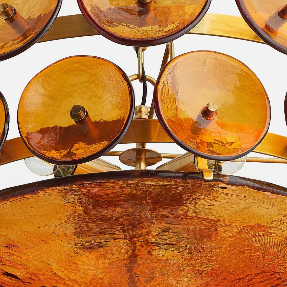 Detail of amber glass discs on brass studs above the wide textured bowl, with bulb holders visible, on this Clérachic chandelier.