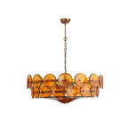 Amber and gold Clérachic chandelier hanging from a brass canopy and chain on a plain white background, unlit.