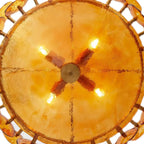 Looking up into the glowing amber bowl of this Clérachic chandelier, with four lit bulbs and a cross-shaped brass fitting.