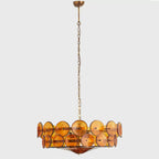 Small amber disc chandelier from Clérachic on a long thin chain, hanging in a grey studio space.