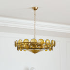 Distance view of a green-gold Clérachic chandelier on its chain and canopy, in a white panelled room with cornice mouldings.