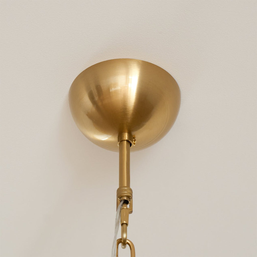 Brushed gold ceiling canopy and the top of the hanging rod on a Clérachic chandelier, against a plain white ceiling.