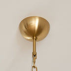 Brushed gold ceiling canopy and the top of the hanging rod on a Clérachic chandelier, against a plain white ceiling.