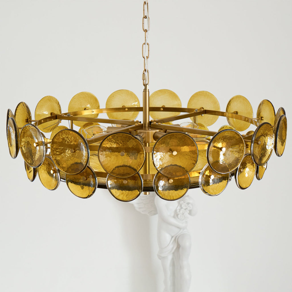 Green-gold disc chandelier from Clérachic from above the discs, showing the gold spoked ring and a white statue behind.