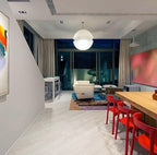 This Clérachic pendant hangs in a wide open-plan room with red dining chairs and large windows onto a dark garden.
