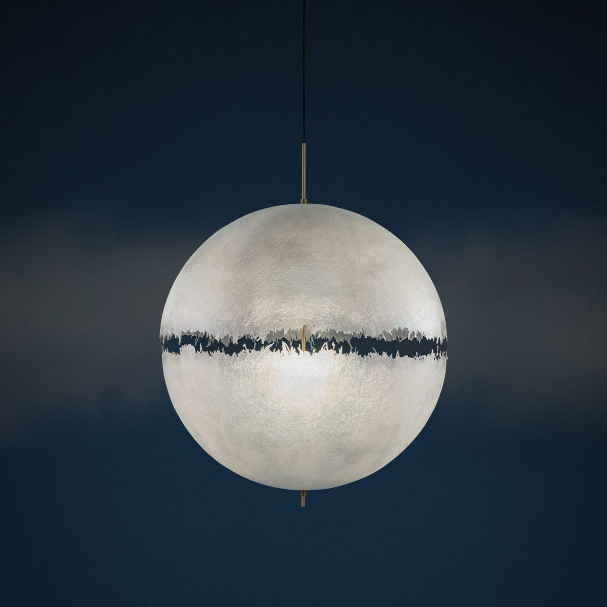 Pale sphere with a dark jagged band, this Clérachic pendant seen against a deep navy background in a studio-style shot.