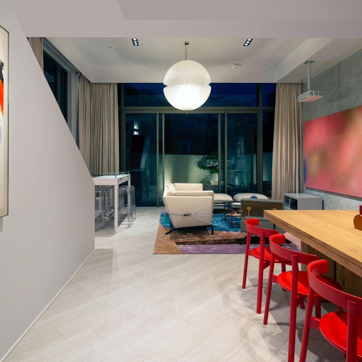 Distant view of this Clérachic pendant hanging in a long room with red chairs and a wooden table, large windows behind.