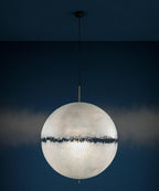 Same sphere from this Clérachic pendant with a soft glow on the navy wall behind, showing the dark band across its middle.