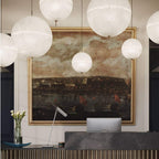 Spheres of different sizes hang in front of a gilt-framed painting, a close view of this Clérachic pendant above a reception desk.