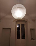 This Clérachic pendant hangs in a vaulted room with a pair of tall doors, its sphere glowing softly in the dim light.