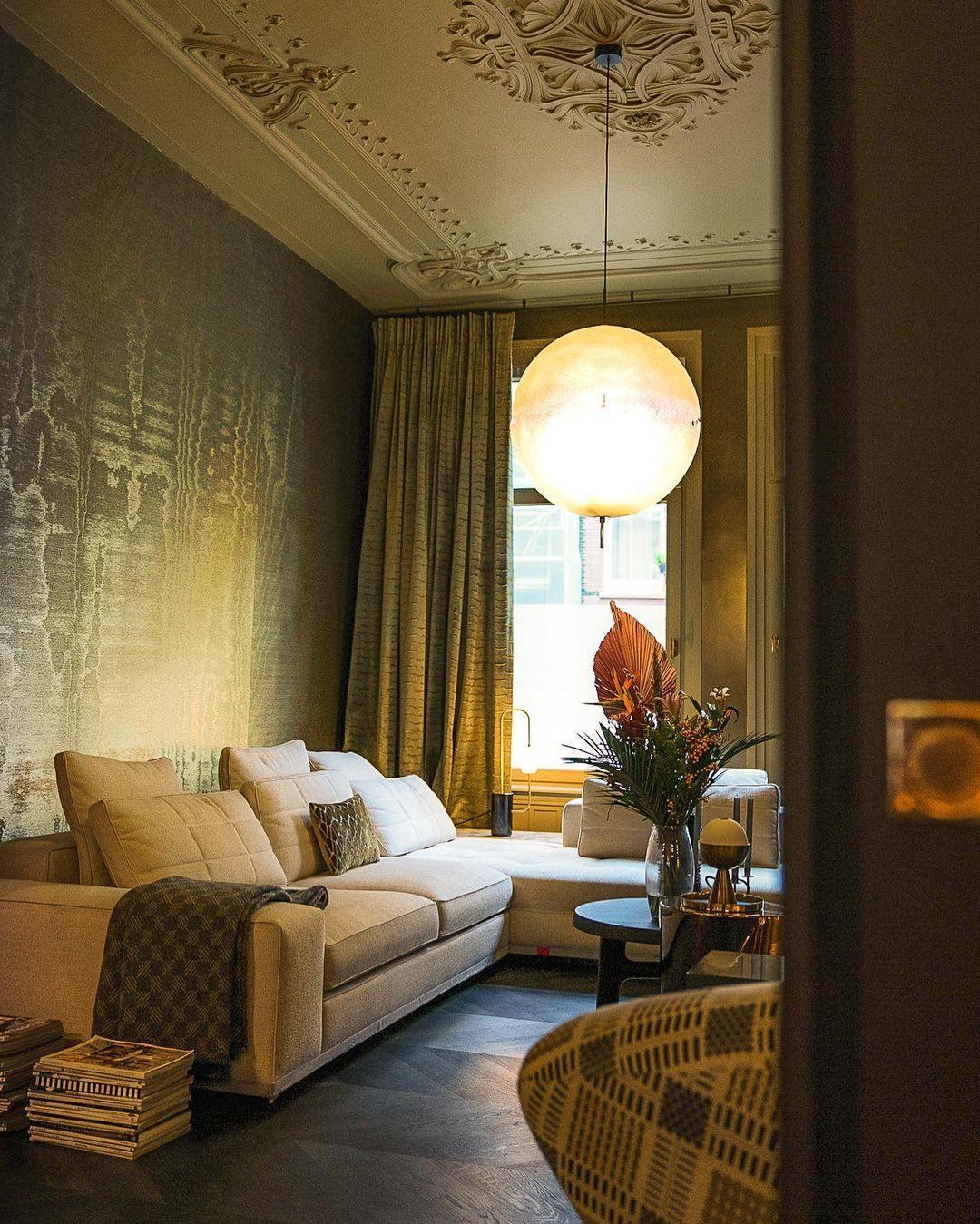 This Clérachic pendant glows warm in a room with ornate plaster ceiling, olive wallpaper and a cream sofa.