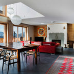 This Clérachic pendant hangs in an open-plan living room with a wooden table and a red sofa, beside a second sphere.