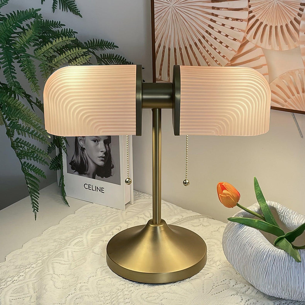 Close view of this Clérachic gold table lamp with pink ribbed shades, standing on a white lace cloth by a ceramic bowl.
