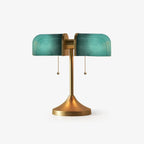 In this photo, a Clérachic gold table lamp with turquoise-green ribbed glass shades and two pull chains, on a plain white backdrop.