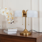 This Clérachic gold table lamp with white ribbed shades stands on a walnut chest, with a tall orchid and two books beside it.