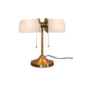 Pictured here, a Clérachic gold table lamp with warm white ribbed shades, lit, with a black cord trailing from its flared gold base.
