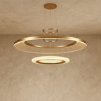 Clérachic two-ring brushed gold LED chandelier with a large mesh-filled ring above a smaller glowing disc, on a ceiling canopy.