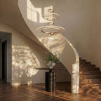 Clérachic three-tier gold ring chandelier hanging in a stairwell above a round table, vase and herringbone floor.