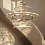 Close view of a Clérachic three-tier gold ring chandelier, showing mesh acrylic discs and warm LED edges in a stairwell.