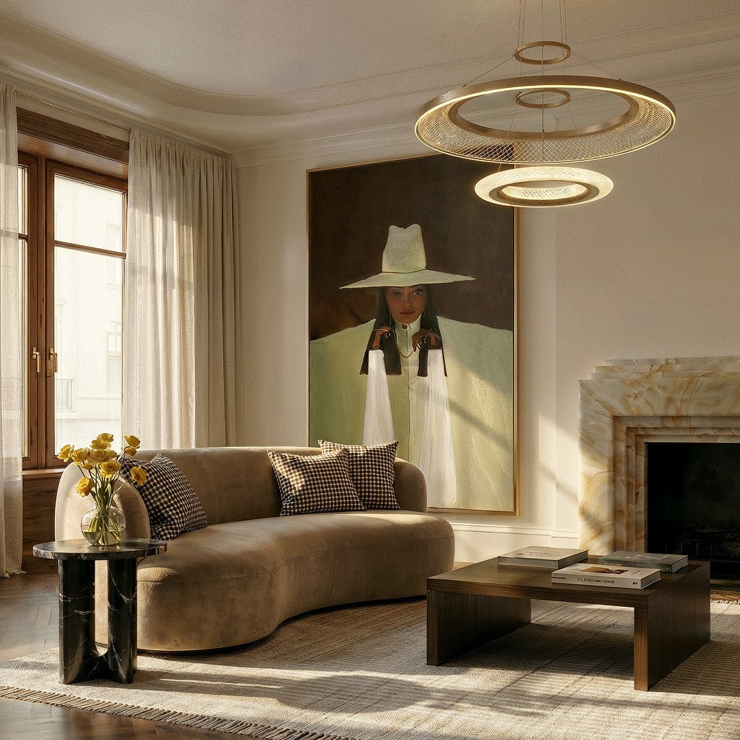 Clérachic two-ring gold LED chandelier above a curved velvet sofa and marble fireplace in a bright living room.