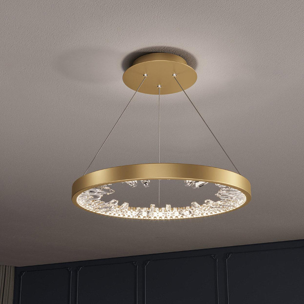 Gold Clérachic ring pendant light with clear glass pieces inside the band, seen from slightly below against a grey ceiling.