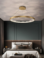 Gold Clérachic ring pendant light over a bed in a dark green room with wood slats and a cream bedspread.