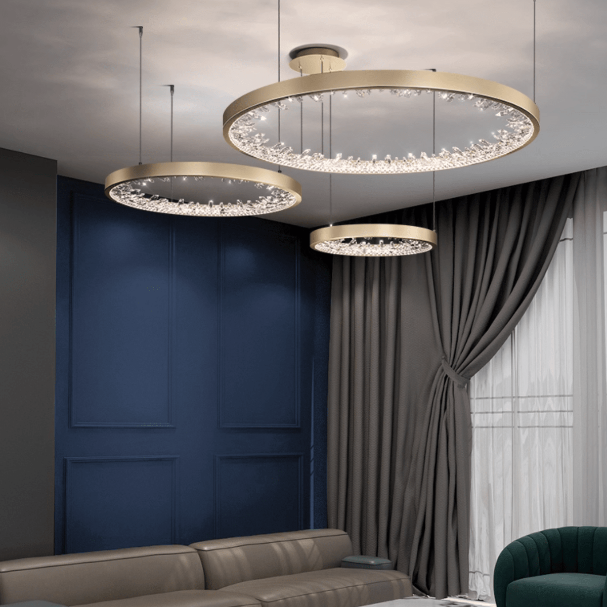 Three gold Clérachic ring pendants of different sizes lit above a blue panelled wall, grey curtains and a leather sofa.