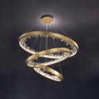 Three gold Clérachic rings stepped down from one ceiling plate, with clear glass pieces lit around each band against a dark backdrop.