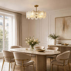 Gold semi flush Clérachic ceiling light with rippled glass discs, hanging above an oval marble dining table and boucle chairs.