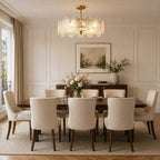 Lit Clérachic ceiling light over a long dark dining table with upholstered chairs, in a panelled room with a framed landscape.