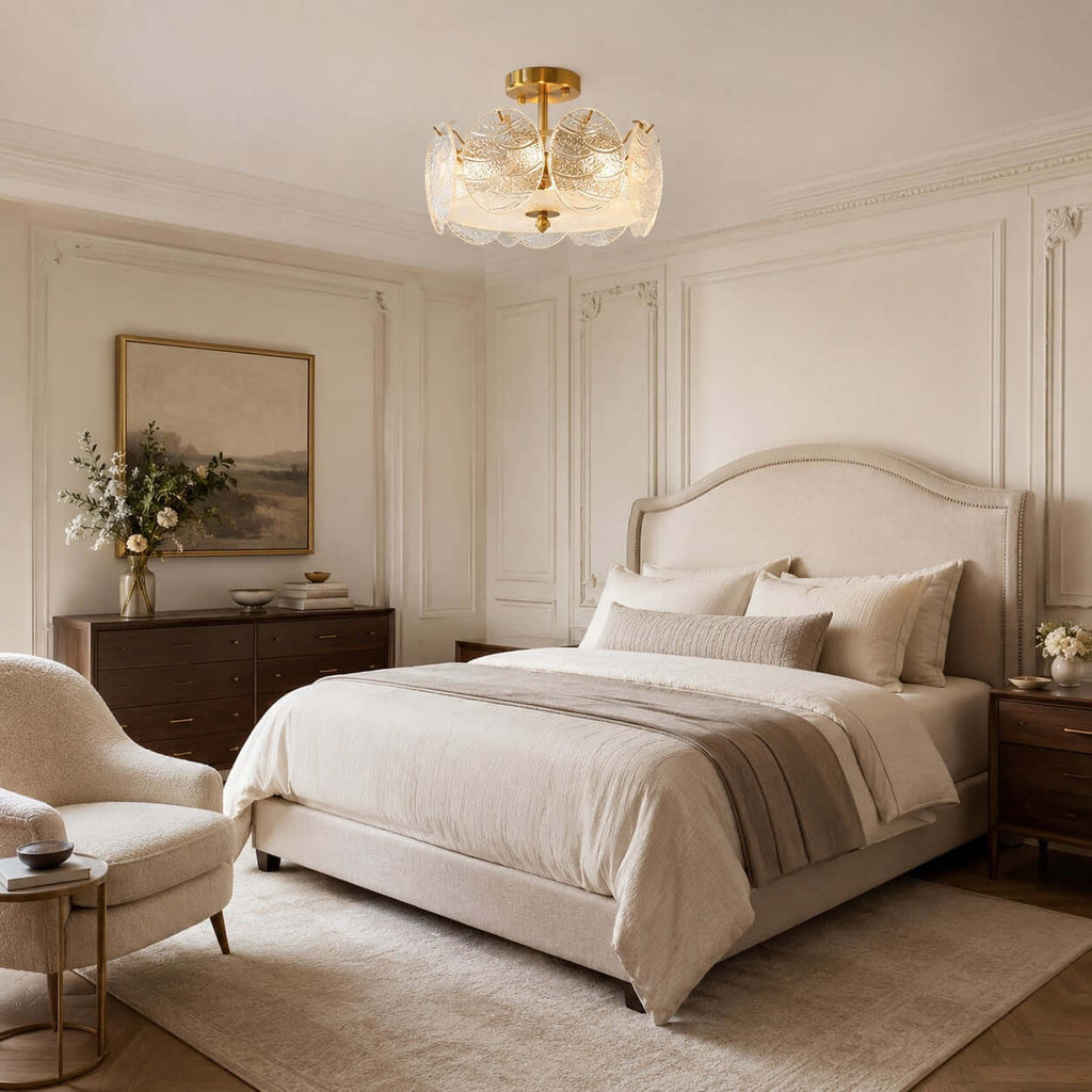 Textured glass discs on a Clérachic ceiling light, seen above a bed with a cream cover, a dark wood chest and a soft armchair.