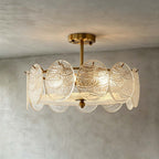 Front view of a lit Clérachic ceiling light with textured glass discs and a gold stem against a grey limewash wall and ceiling.