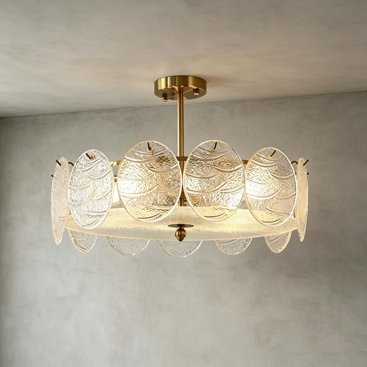 A Clérachic semi flush ceiling light with a gold canopy and overlapping glass discs, lit and photographed against a grey limewash wall.