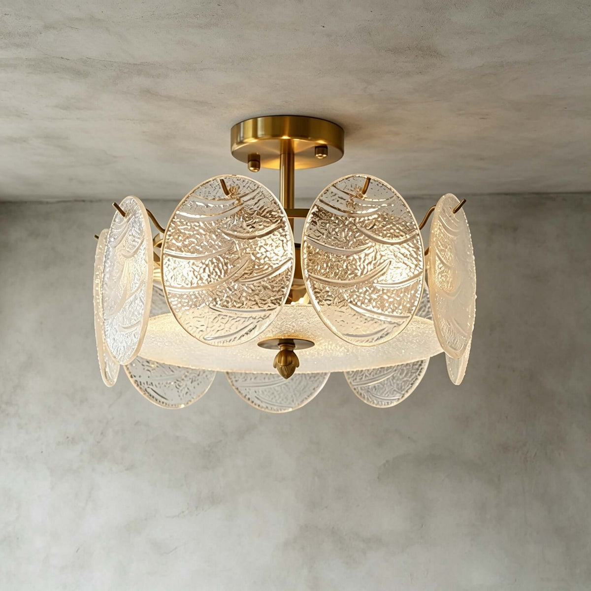 Angled close view of this Clérachic ceiling light, its gold canopy and textured glass discs glowing against a grey textured ceiling.