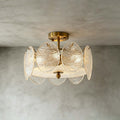 Slightly lower angle on a Clérachic gold semi flush light, showing the rippled glass discs and frosted base against a grey wall.