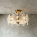 Slightly lower angle on a Clérachic gold semi flush light, showing the rippled glass discs and frosted base against a grey wall.