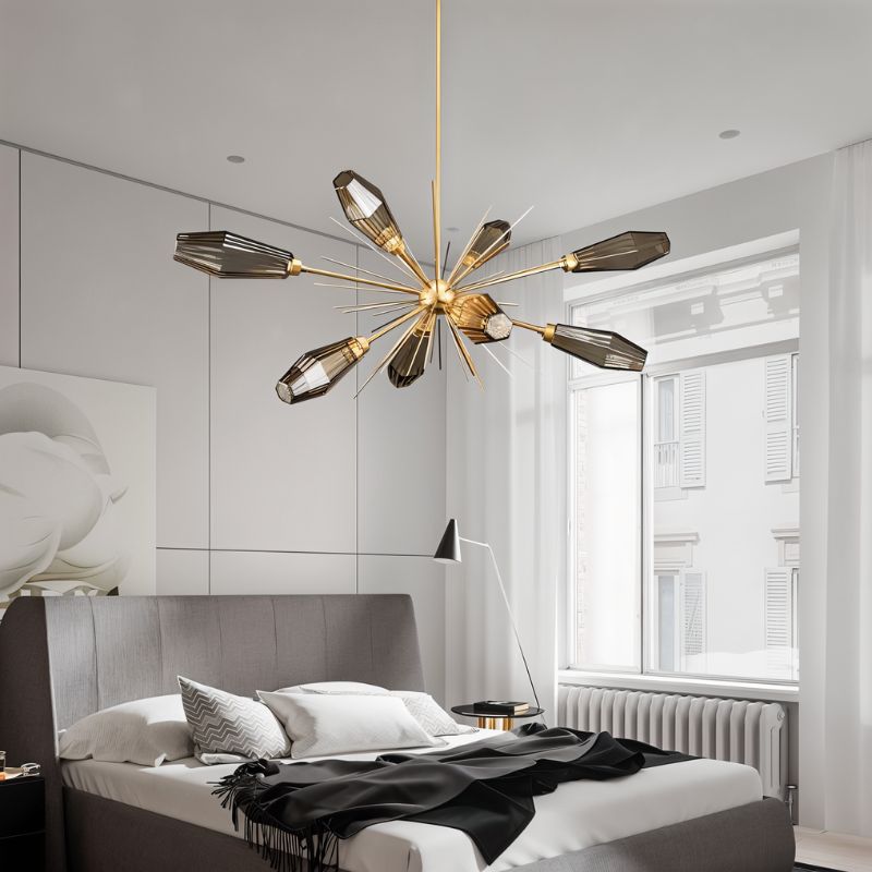 Clérachic gold starburst chandelier with smoked glass heads above a grey upholstered bed in a white bedroom.