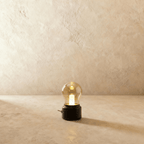 This Clérachic table lamp in a black base glows warmly, its vintage-style glass bulb shade lit softly.