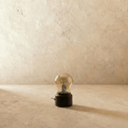 Clérachic's table lamp in a black base sits unlit, its clear glass bulb shade catching the light.