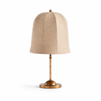 Close front view of this Clérachic table lamp, with a tall bell-shaped linen shade, a bamboo-wrapped stem and a gold base.