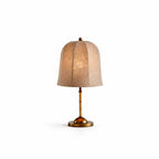 A smaller Clérachic table lamp with a glowing linen shade and a gold base, shown on a plain white backdrop.
