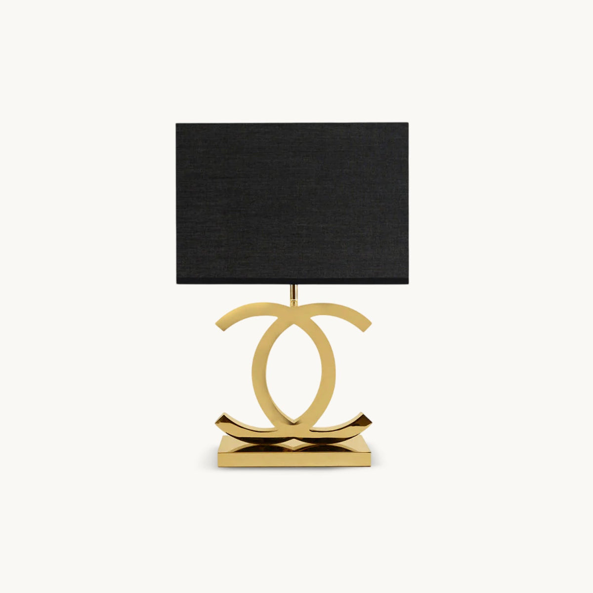 Clérachic gold table lamp with a black rectangular fabric shade on a polished stainless steel base of two interlocking curved loops, on white.