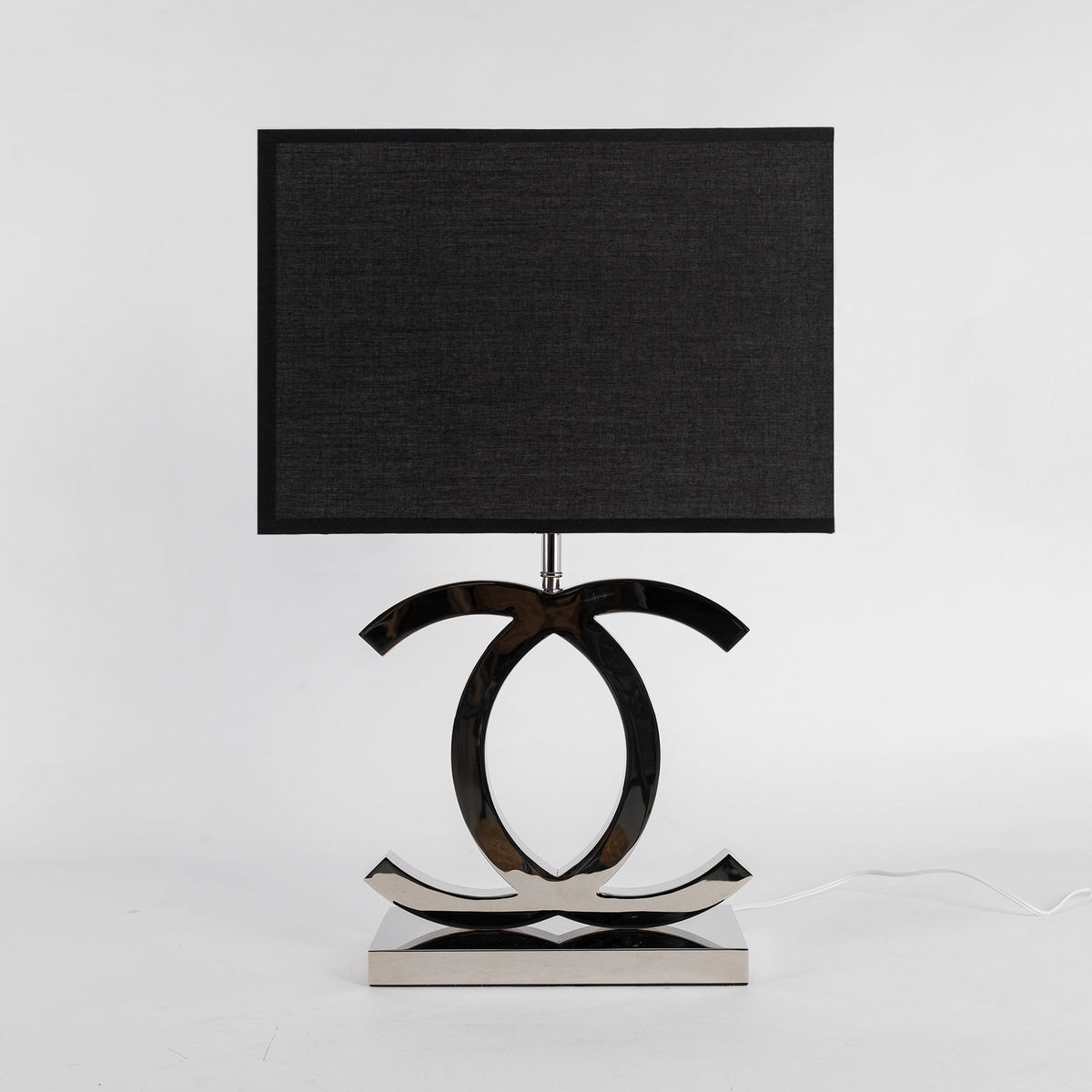 Clérachic chrome table lamp with a black rectangular shade and a polished stainless steel base, against a pale grey backdrop.