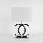 Front view of a Clérachic chrome table lamp with a white shade and a thin white cord, against a light grey backdrop.