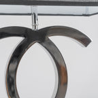 Close view of the polished stainless steel loops below the shade stem on this Clérachic table lamp, against a pale backdrop.