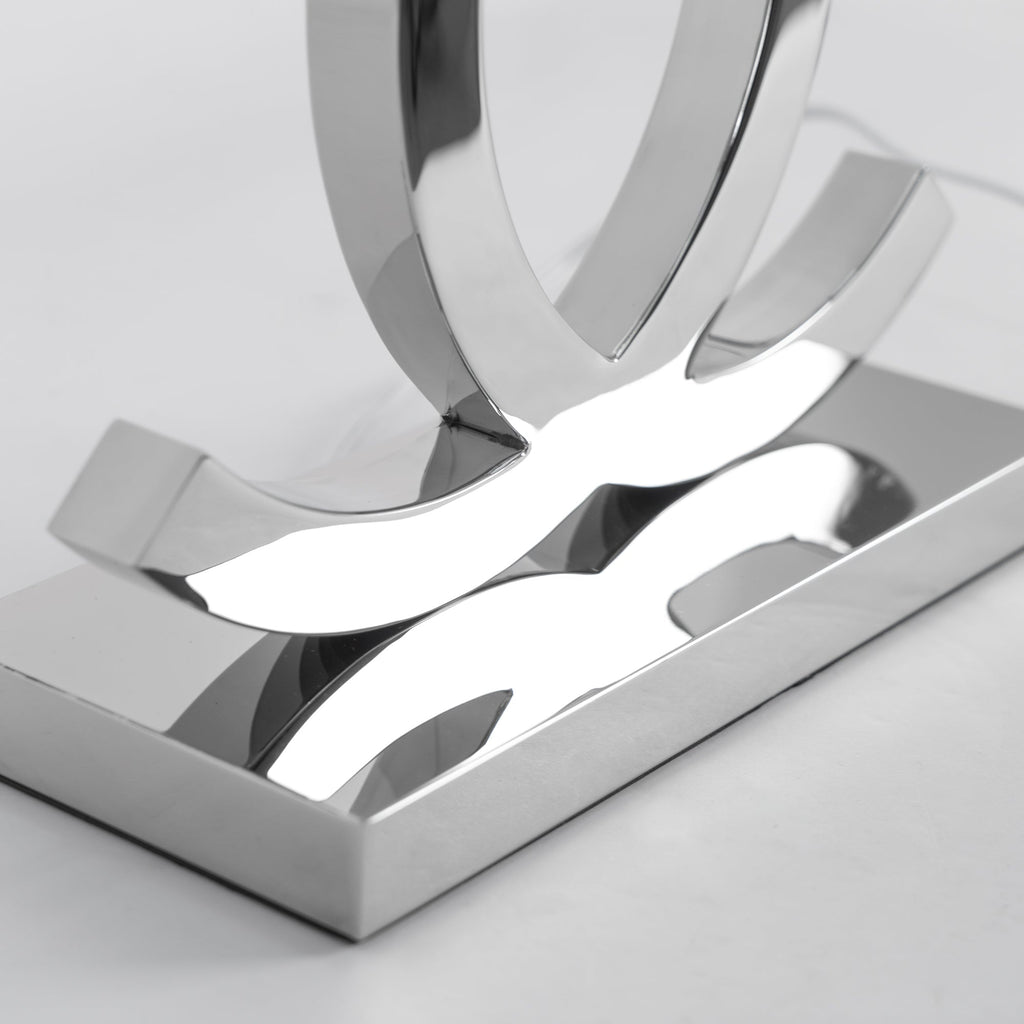 Close view of the mirror-polished steel base and the lower ends of the loops on this Clérachic table lamp.