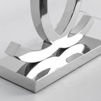 Close view of the mirror-polished steel base and the lower ends of the loops on this Clérachic table lamp.