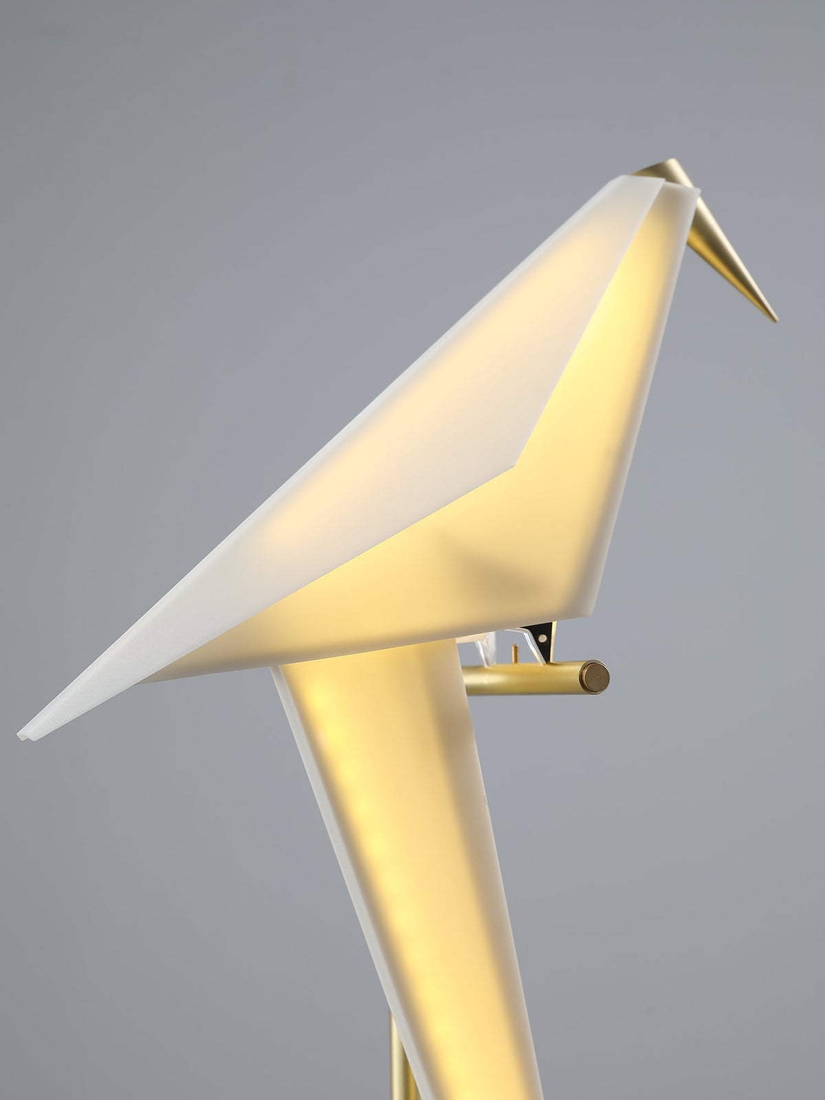 Close view of the lit folded paper bird of this Clérachic table lamp, the warm light glowing through its translucent body.