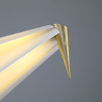 Close view of the gold cone tip at the end of the bird's tail on this Clérachic table lamp, with light along the fold.