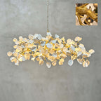 A Clérachic petal chandelier hung on a gold chain against a grey plaster wall, with a small inset detail of the textured gold branches.